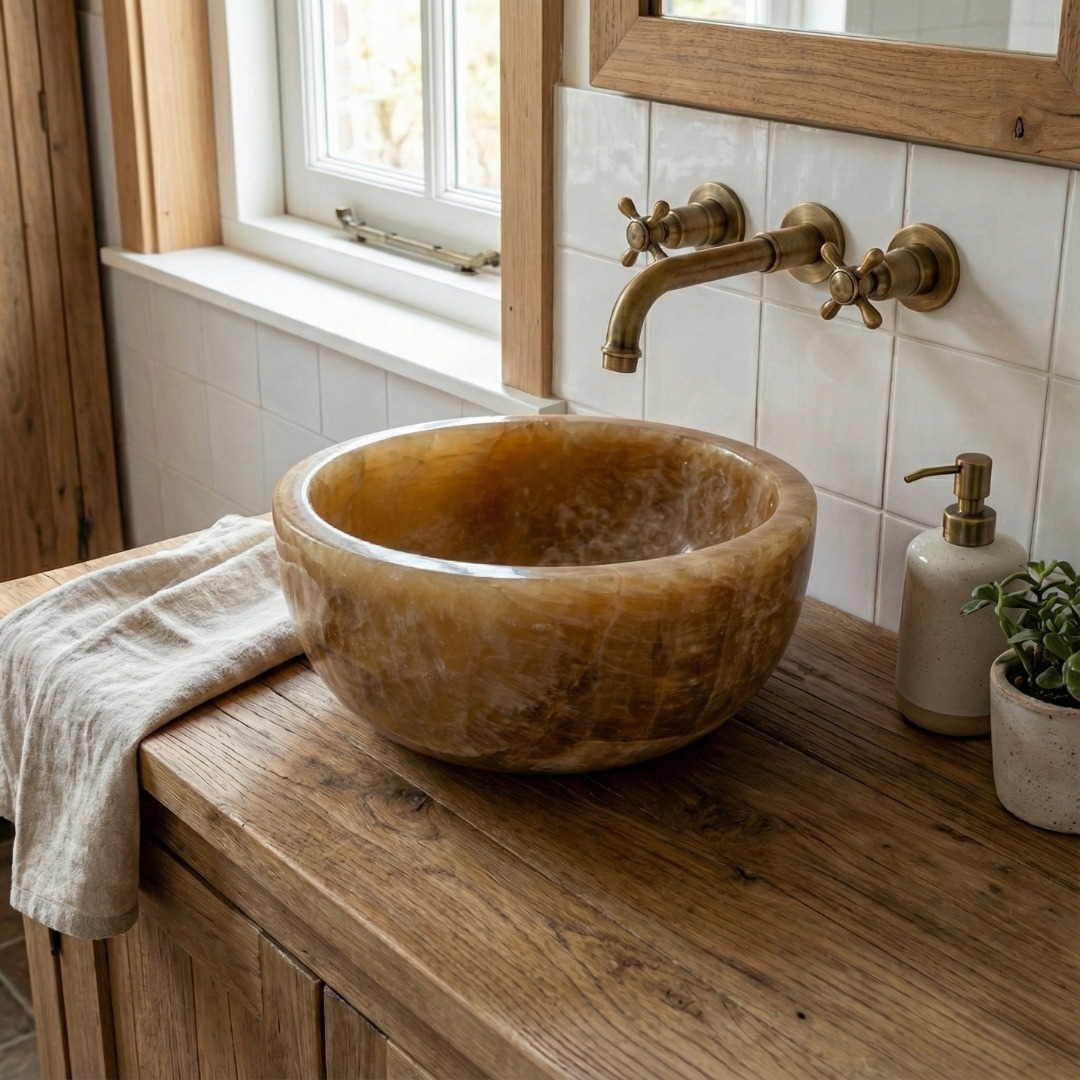 Ronde honinggele onyx waskom 25 cm x 12 cm op een vergrijsd houten blad met rvs kraan in een lichte badkamer. - view 3