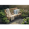 Teak Stationsbank 120 cm in een mooie tuin met bloemen en kussens en kleden sfeervol op de bank gelegd. 