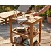 Luxe teakhouten serveerwagen op een zonnig terras, gestyled als buitenbar met wijn en hapjes. Een hand pakt een wijnglas van het bovenblad.
