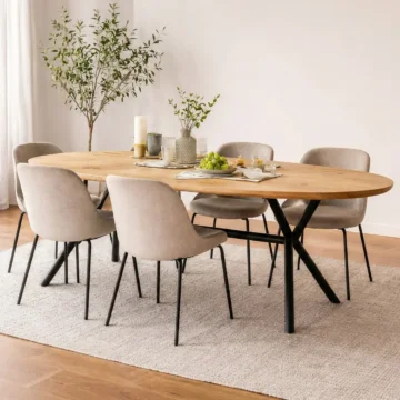 Ovale eikenhouten eettafel met zwart metalen spider-poot en beige velvet eetkamerstoelen in een modern interieur.
