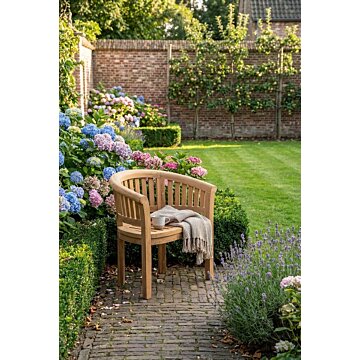 Massief teakhouten tuinstoel Peanut met ronde rugleuning en verticale spijlen, zijaanzicht van uniek kuipmodel voor in de tuin.