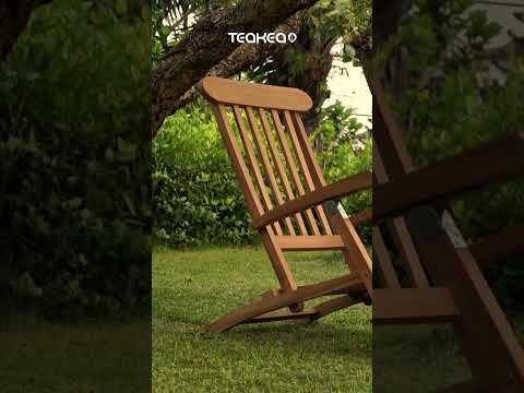 Klassieke teakhouten deckchair met zilverkleurig RVS beslag op een stenen terras, inclusief voetensteun en naast een rotan bijzettafel - view 3
