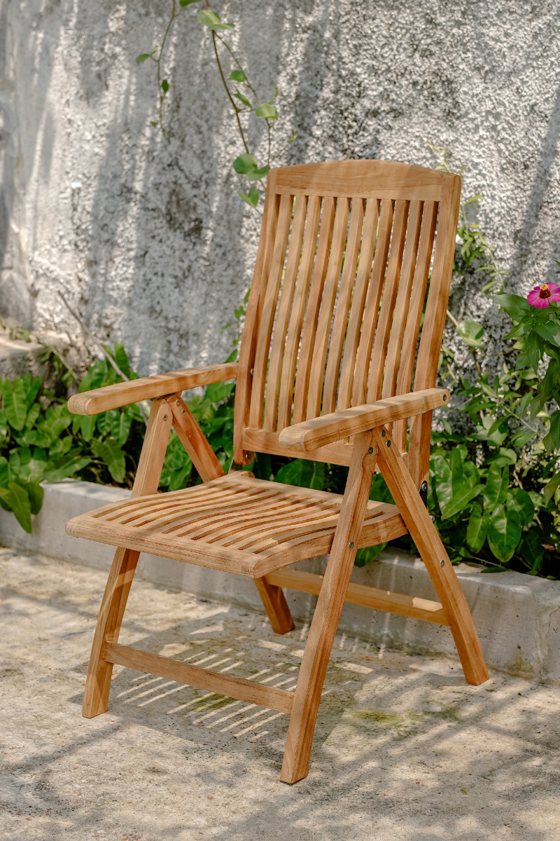 Houten inklapbare tuinstoel en bijzettafel van teak op een vlonder in een sfeervolle tuin met bloemen, een bakstenen muur en een pergola. - alternate view
