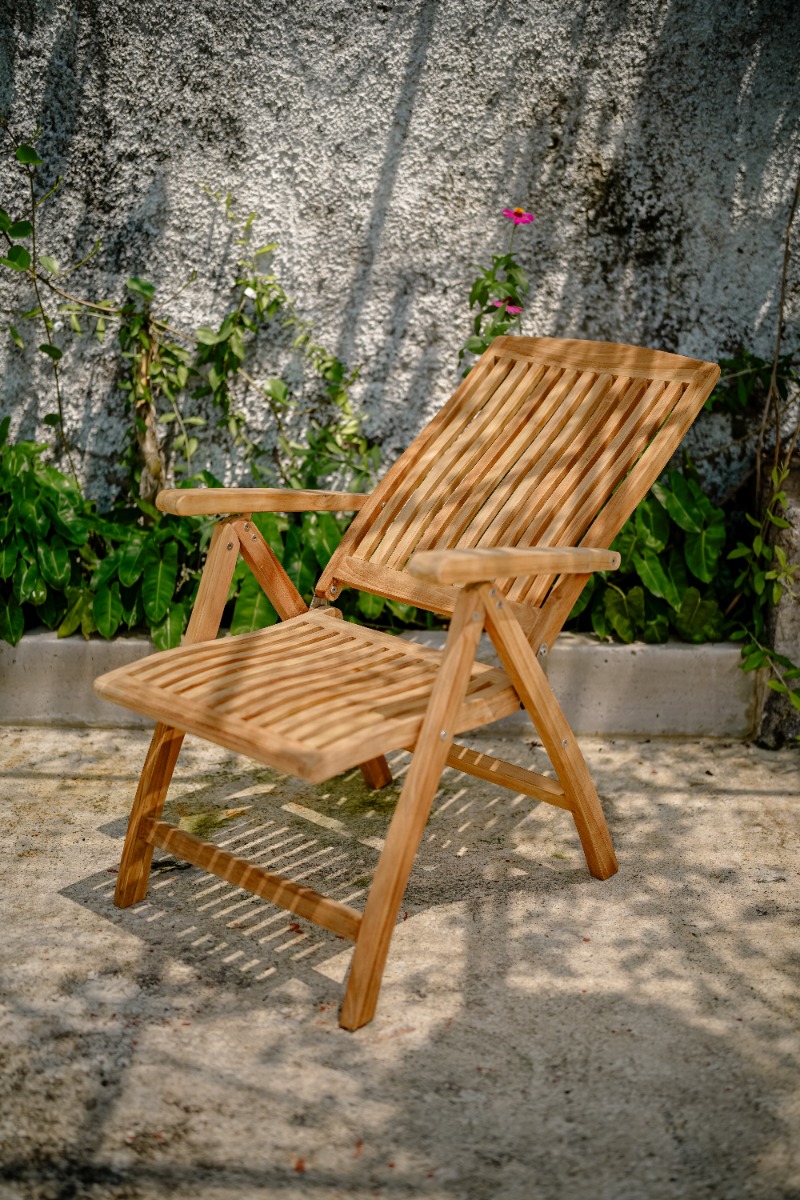 Houten inklapbare tuinstoel en bijzettafel van teak op een vlonder in een sfeervolle tuin met bloemen, een bakstenen muur en een pergola. - view 3