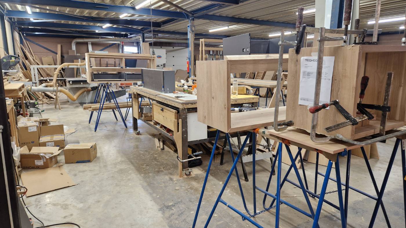 Coatingafdeling van Teakea met eiken kastdelen in de lijmklemmen op werkbanken